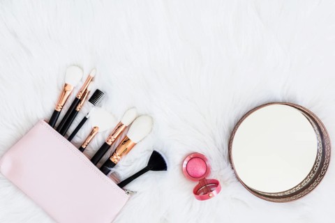 Makeup brushes bag with pink compact powder round mirror fur backdrop