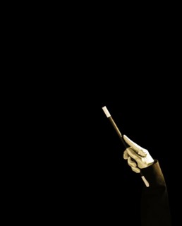 Magician s hand holding magic wand against black background