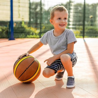 Happy boy playing basketball outdoors