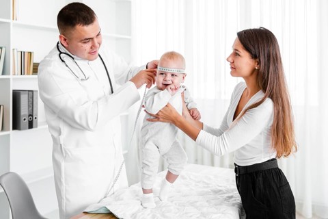 Mother holding baby while doctor looking it