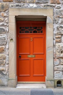 Red front door on an old stone house