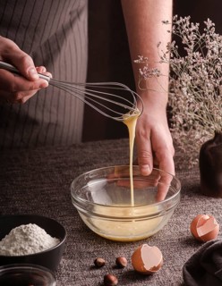 High angle cook whisking eggs bowl