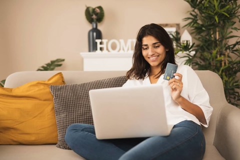 Smiling woman working laptop holding credit card