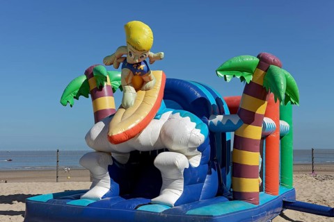 Inflatable bouncy castle with cartoon character Surfer on the beach