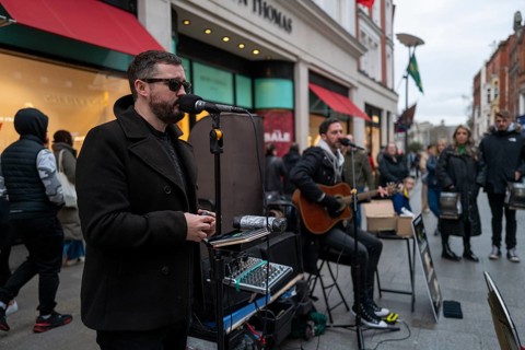 Andrew Kavanagh of Irish group Keywest singing in Grafton street with Andrew Glover in the back ground. Dublin
