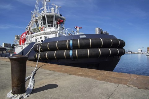 Mooring bollard and the French tug boat VB Mirage showing huge tugboat fenders docked in the seaport of Saint-Nazaire