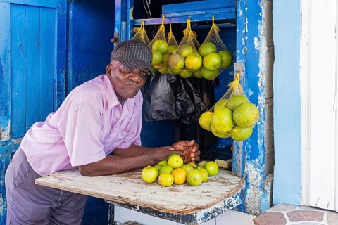 Old local black man selling oranges and lemons at market in the city Georgetown