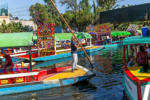 Popular tourist attraction people boating on colourful barges on canal at Xochimiloco