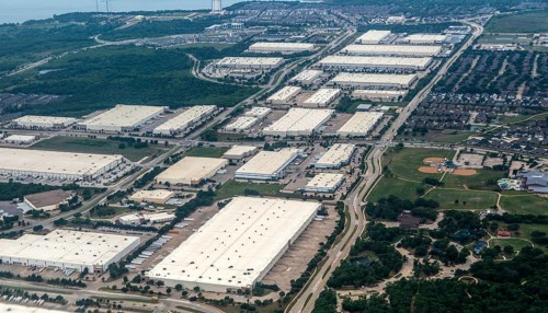 Oblique angle aerial view of large distribution centre logistics warehouse buildings on landing approach to Fort Worth