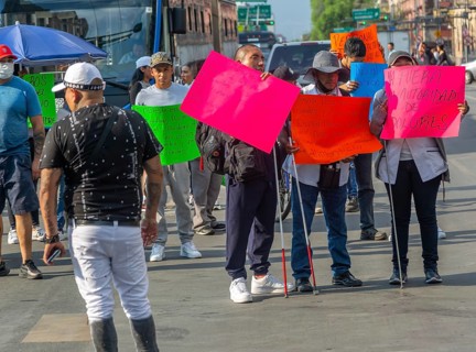 Blind visually impaired protestors holding placards block traffic on busy city centre road