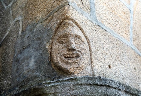 Carved face in granite block on corner of building