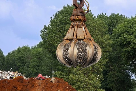 Orange peel grab of dock crane grabbing recycled scrap metal at recycling export terminal in the port of Ghent