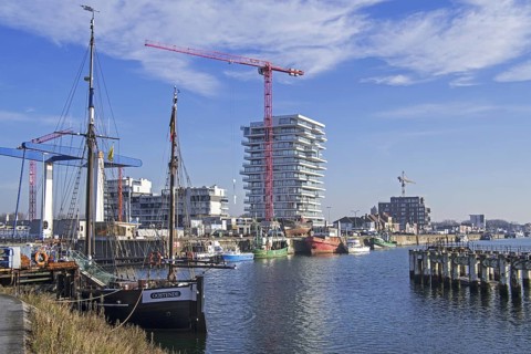 Two-master sailing vessel Nele and new flats being build for real estate project Oosteroever in the Ostend harbour along the Belgian North Sea coast
