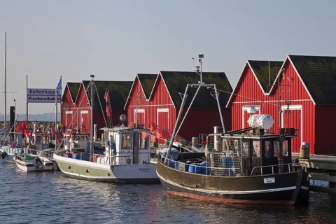 Fishing boats moored in front of red wooden huts in the harbour of Boltenhagen along the Baltic Sea