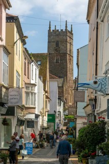 Shops in historic buildings along alleyway with tower of church of St Saviour