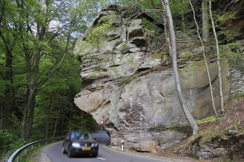 Car driving under the sandstone rock formation Predigtstuhl in Berdorf