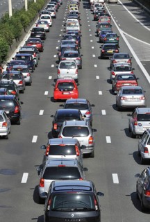 Cars queueing in highway lanes at approach slip road during traffic jam on motorway during summer holidays