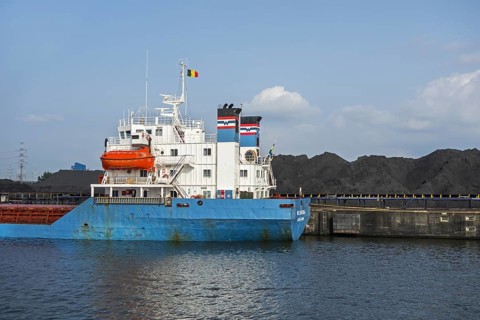 Bulk carrier docked in front of heaps of coal at SEA-invest