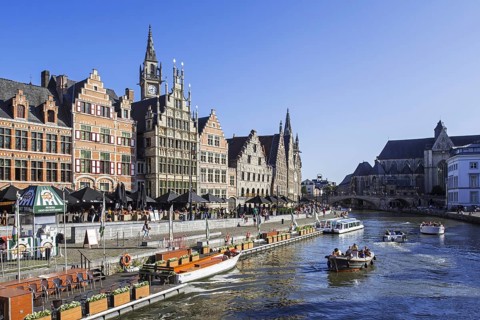Sightseeing boats with tourists on the river Lys with view over guildhalls at the Graslei