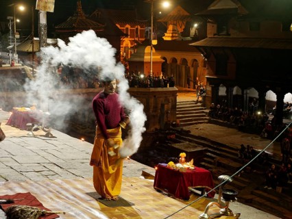 Hindu priest performing a ritual with smoke at night in front of the Pashupatinath temple