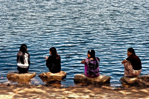 Women squatting on stones by the lake