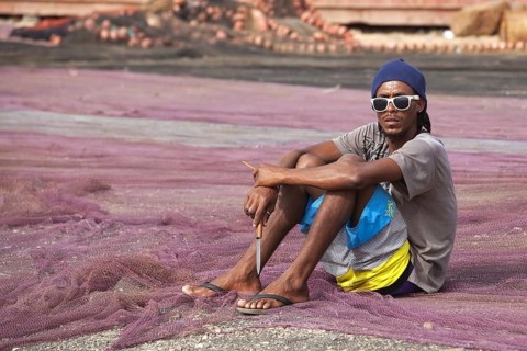 Creole fisherman mending fishing nets in the harbour of the fishing village Palmeira on the island of Sal
