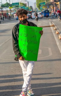 Protestor holding placard blocks traffic on busy city centre road