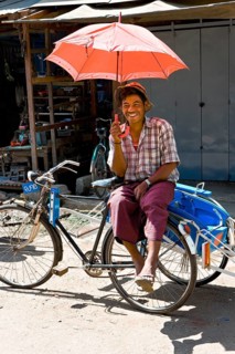 Rickshaw driver with red umbrella waiting at the market