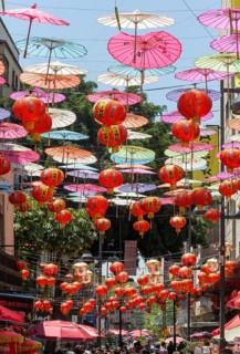 Red paper Chinese lanterns and umbrellas hanging above the street in Chinatown