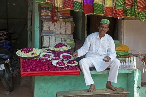 Vendor in front of shop selling scarfs and flowers as gifts for offerings near the Nizam-Ud-Din shrine in Delhi