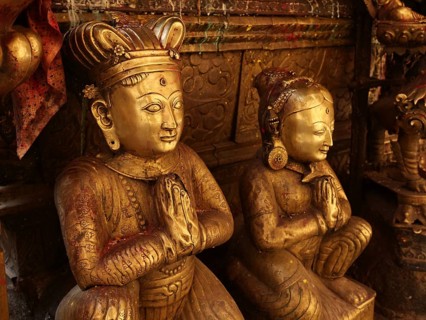 Golden metallic statues of a man and a woman sitting and praying