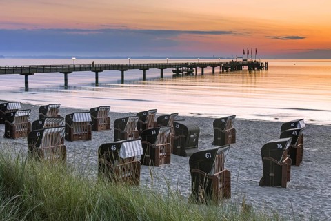 Roofed wicker beach chairs and wooden pier