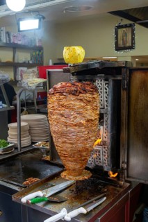 Meat grilling on vertical kebab spit in fast food street restaurant