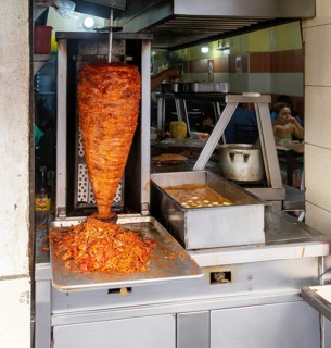 Meat grilling on vertical kebab spit in fast food street restaurant