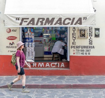 Woman walking past small pharmacy shop