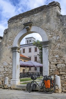 Touring bicycle in front of remains of ancient Roman city gate in the town Pore?