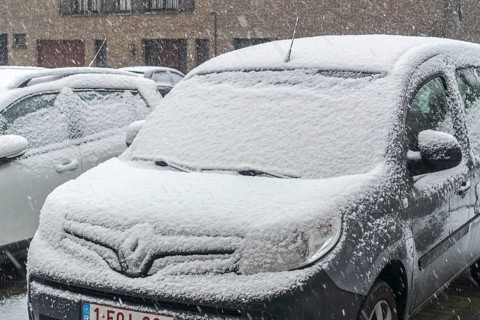 Parked cars covered in snow during unexpected late snow shower in March 2023