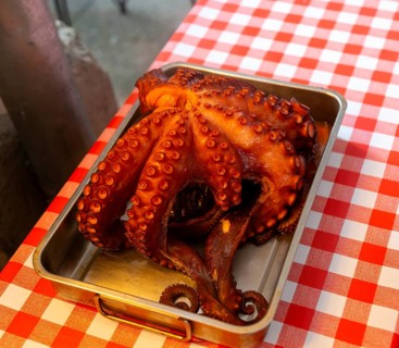 Cooked octopus on display on restaurant table with red and white checked table cloth