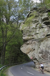 Cyclist riding under the sandstone rock formation Predigtstuhl in Berdorf