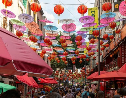Red paper Chinese lanterns and umbrellas hanging above the street in Chinatown
