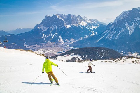 Skiers and snowboarders on the panoramic run with a view of the Zugspitze