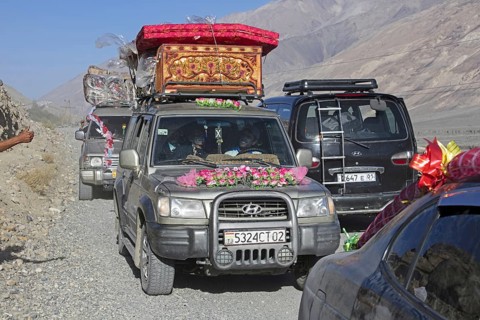 Decorated vehicles loaded with presents on their way to a traditional wedding on the Pamir Highway