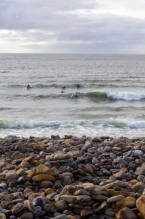 Stones on the beach as surfers ride the waves along the Wild Atlantic way. Strandhill