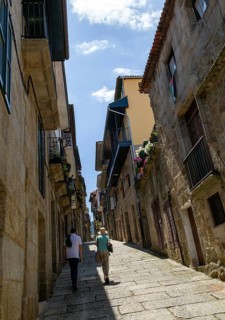 Two people walking past houses on steep narrow street in medieval town
