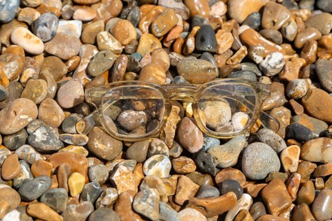Pair of plastic spectacles glasses washed up on shingle beach