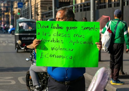 Protestor holding placard blocks traffic on busy city centre road