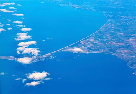 Oblique aerial view through plane window of Chisel Beach tombolo and Portland Bill island