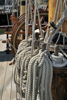 Steering wheel and ropes coiled around belaying pins aboard the Grand Turk