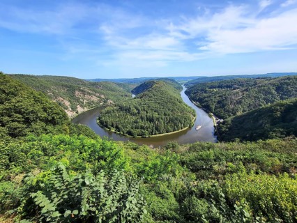 Aerial view of the Saar Loop. The Saar winds through the valley and is surrounded by green forests. Orscholz