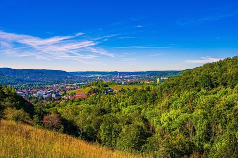 View over the city of Jena from the Galgenberg with the Kernberge in the background under blue sky and veil clouds